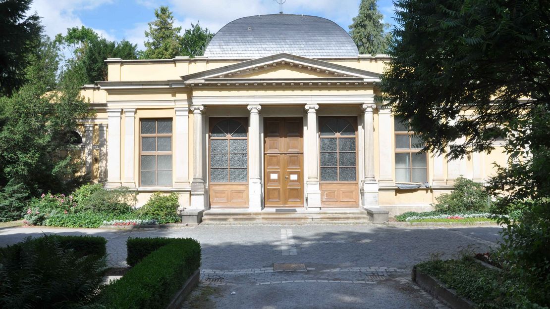 Trauerhalle. Gebäude mit viersäuligem Eingangsportal und metallener Kuppel.