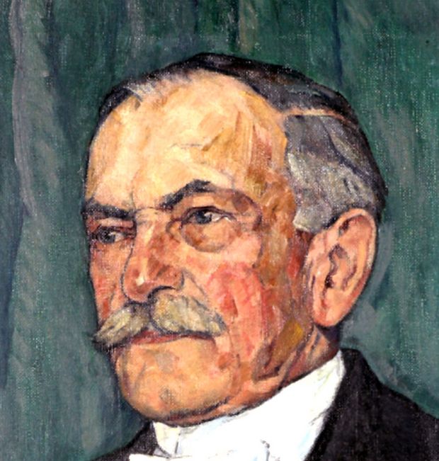 Gesicht eines hellhäutigen Mannes mit grauen Haaren und einem grauen Schnauzer auf dunkel-grün-blauem Hintergrund